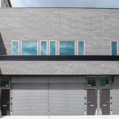 東大阪市高井田中に建つ木造2階建ての駐車場付きテナント事務所ビル外観。外壁にKMEWフィエルテを採用し、倉庫と事務所を併設した施工事例。