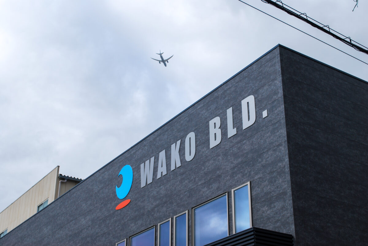 東大阪市高井田中に建つ木造2階建ての駐車場付きテナント事務所ビル外観。外壁にKMEWフィエルテを採用し、倉庫と事務所を併設した施工事例。