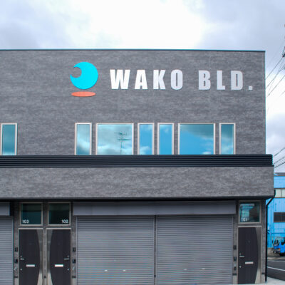 東大阪市高井田中に建つ木造2階建ての駐車場付きテナント事務所ビル外観。外壁にKMEWフィエルテを採用し、倉庫と事務所を併設した施工事例。