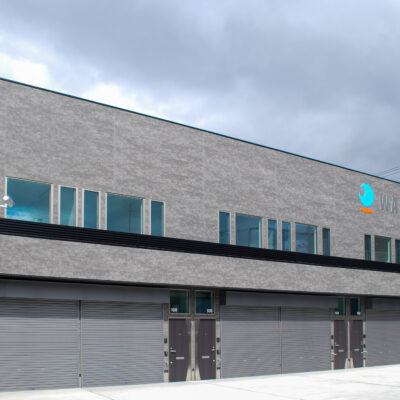 東大阪市高井田中に建つ木造2階建ての駐車場付きテナント事務所ビル外観。外壁にKMEWフィエルテを採用し、倉庫と事務所を併設した施工事例。