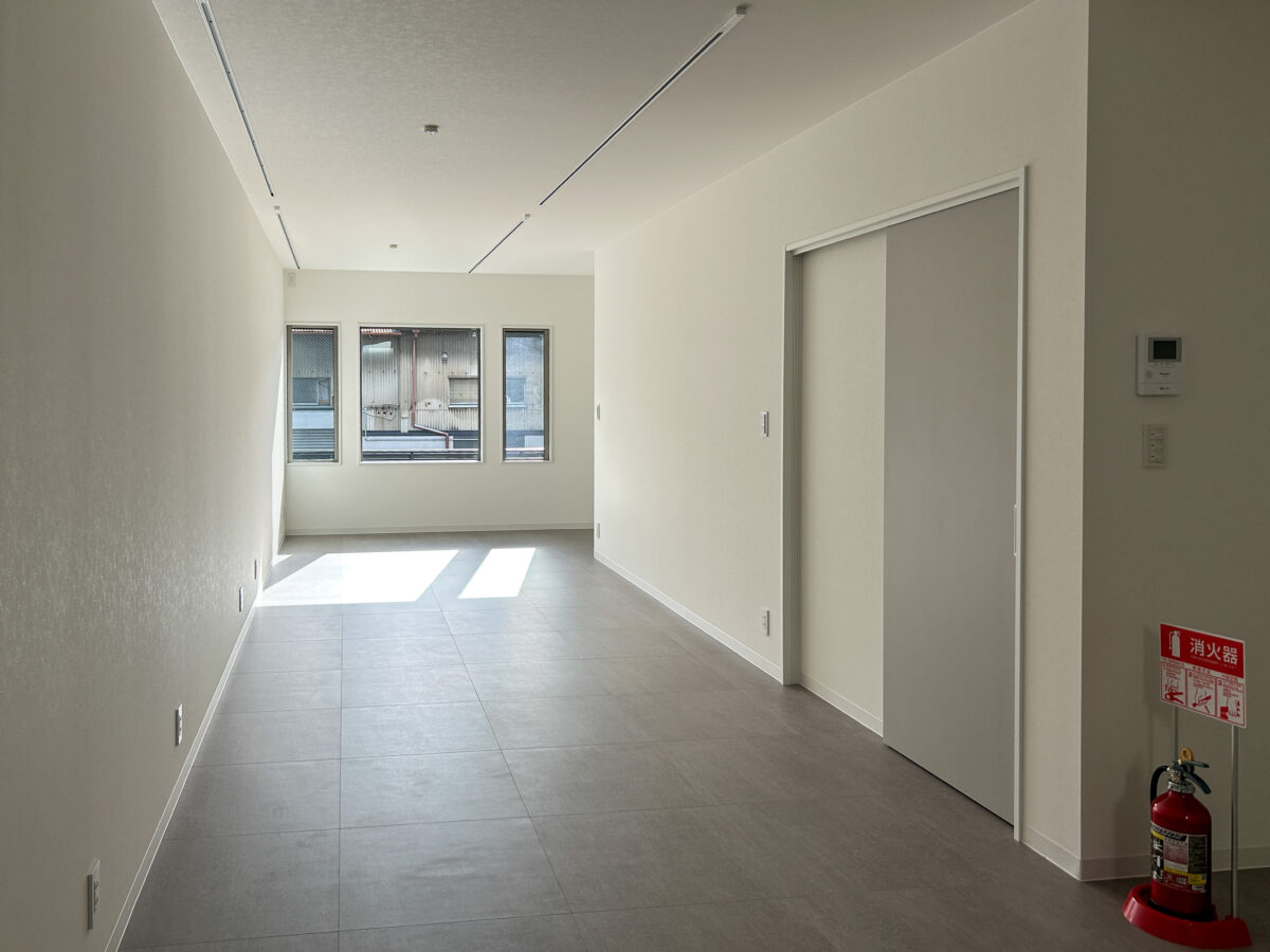 東大阪市高井田中に建つ木造2階建ての駐車場付きテナント事務所ビル外観。外壁にKMEWフィエルテを採用し、倉庫と事務所を併設した施工事例。